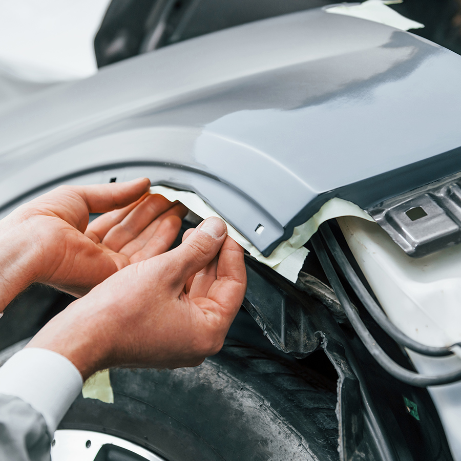 Technician carefully fitting an automotive body panel